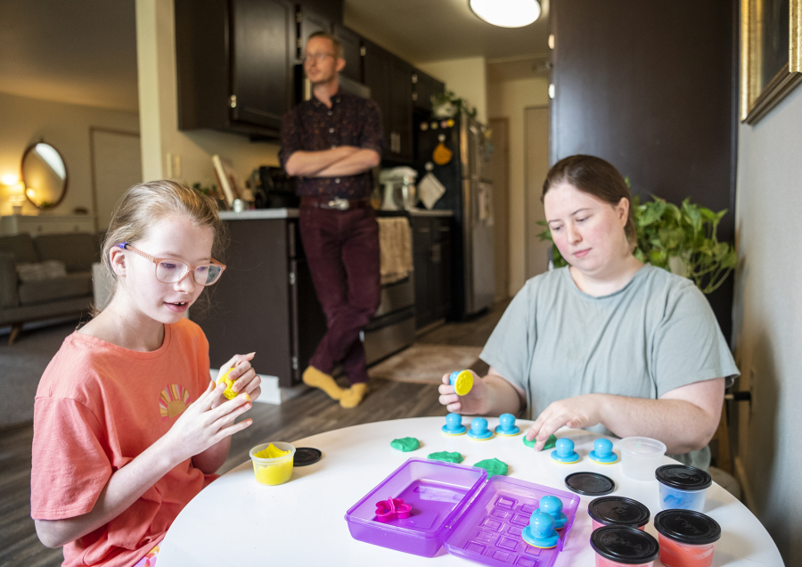 Belle Jackson, 10, left, plays with modeling clay with her mom, Stephanie James, right, as dad Bryant James watches in the kitchen at their home in Vancouver. Belle, who has DiGeorge syndrome, has spent time at home with her parents lately after a rocky start to her school year.