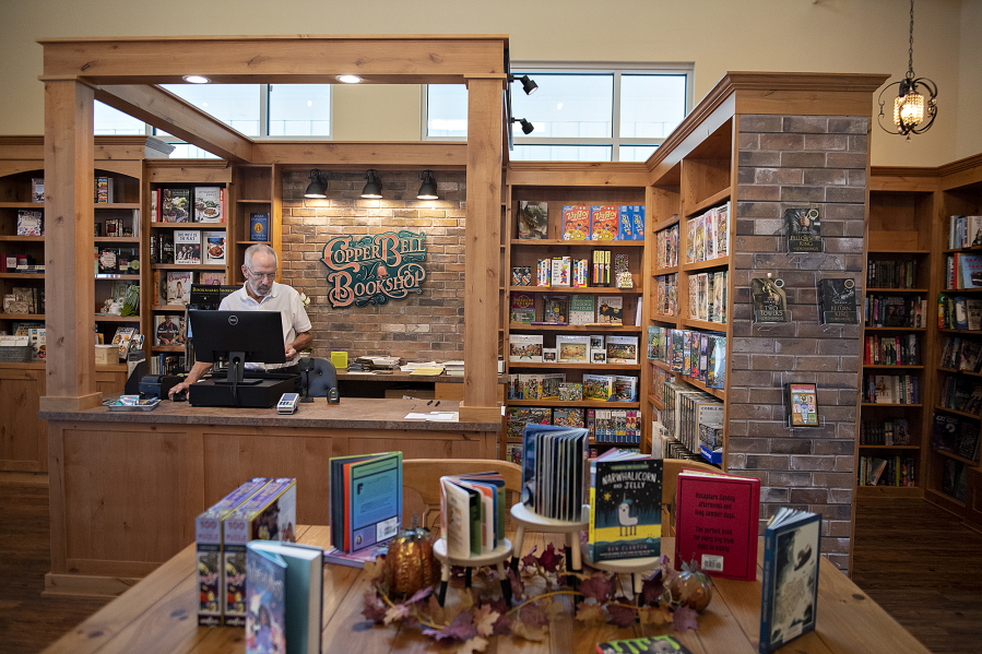 Paul Warnock, co-owner of Copper Bell Bookshop in Ridgefield, works behind the front counter of the newly opened shop. The store opened Oct. 1.  At top, pedestrians stroll past the nearly 1,400-square-foot space that is home to new books.
