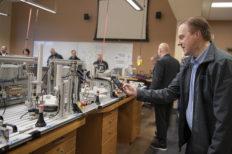 Kris Johnson, president of the Association of Washington Business, right, pauses to take a photo while touring lab rooms at Clark College's Columbia Tech Center campus on Monday morning. The visit was part of a Manufacturing Week bus tour, which highlights the contributions of the state's manufacturing sector.