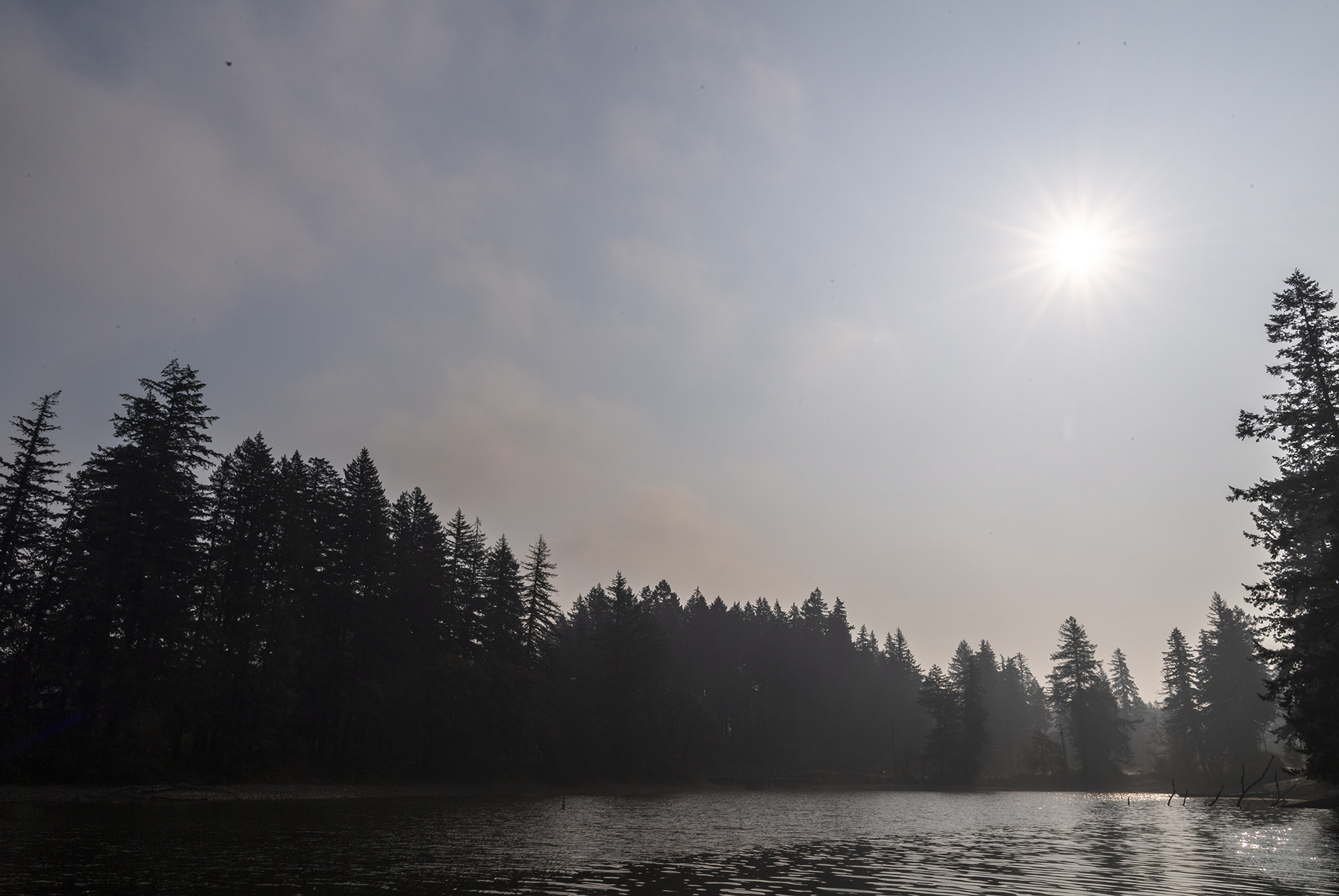 The sun shines through a layer of fog and smoke Tuesday, Sept. 18, 2022, at Lacamas Lake in Camas. Smoke from the Nakia Creek Fire and a morning layer of fog pushed air quality into the unhealthy range.