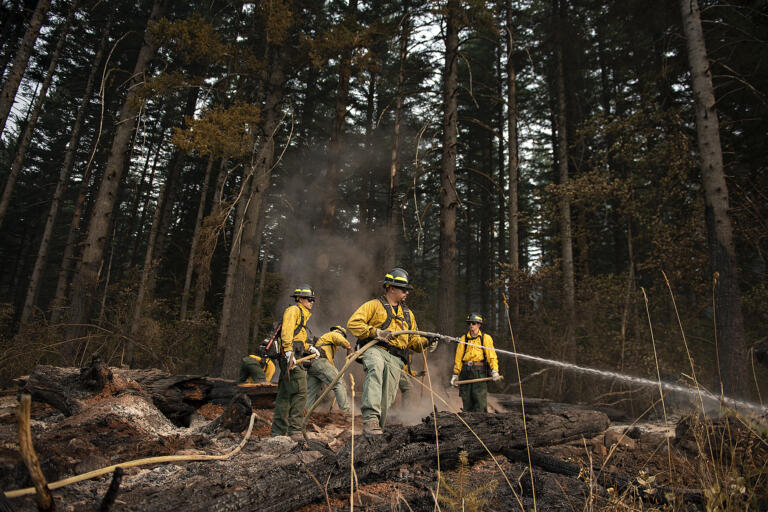 Firefighter Leo Gonzalez, center, sprays smoldering ground in the Camas Creek Watershed while working with colleagues to tackle the Nakia Fire on Wednesday afternoon, Oct. 19, 2022.