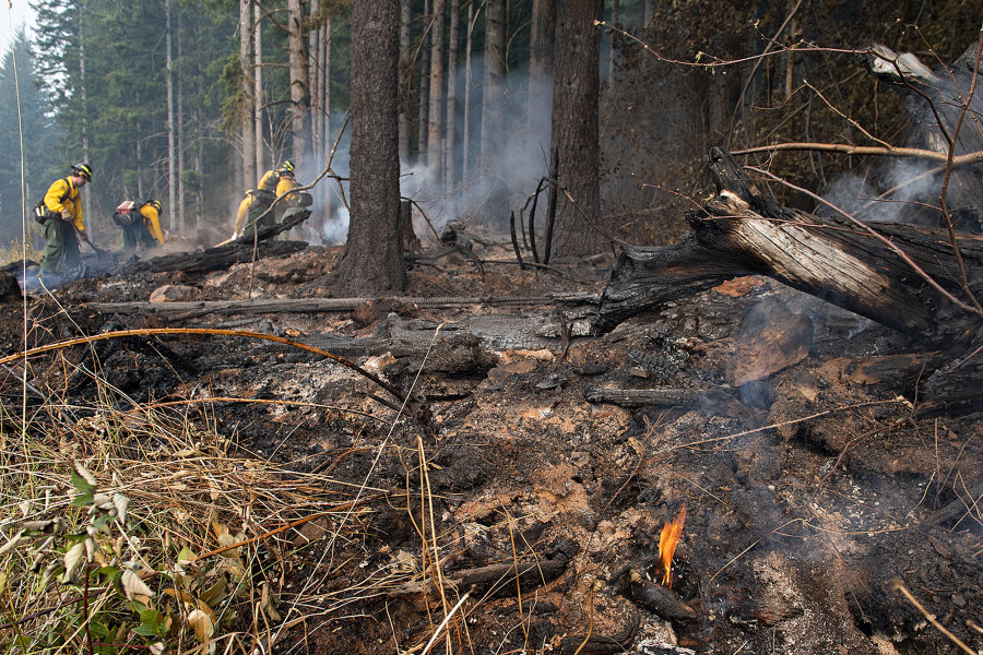A small flame burns in the Camas Creek watershed while firefighters tackle the Nakia Fire on Wednesday afternoon.
