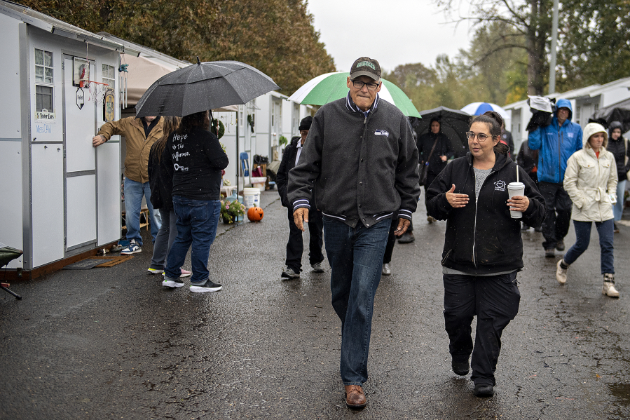 Gov. Jay Inslee, left, strolls with Vancouver's Homeless Response Coordinator Jamie Spinelli during a tour of the Outpost Safe Stay Community Monday morning. Officials are hailing it as a possible model for other cities to address the needs of the unhoused.