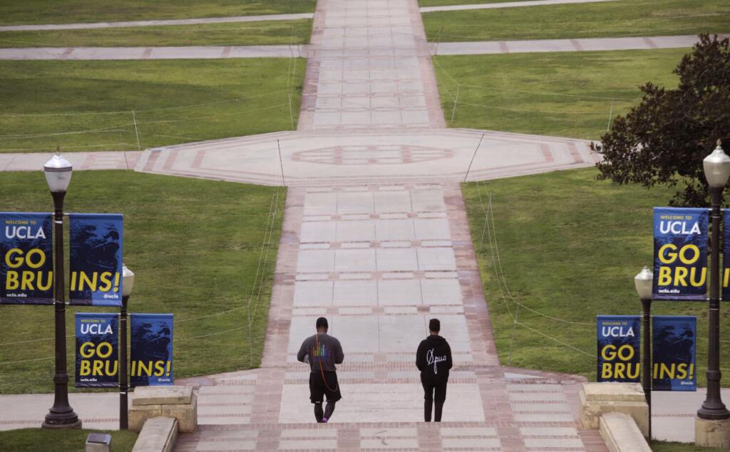 A couple walk through a near empty campus after UCLA canceled in-person classes Tuesday after a former lecturer and postdoctoral fellow sent a video referencing a mass shooting and an 800-page manifesto with "specific threats" to members of the university's philosophy department Monday. "It's the safe thing to do," White said. He was hoping to pick up something from the library but it was closed. Several emails from department leaders and obtained by The Times inform students and faculty that Matthew Harris made threats toward the philosophy department and people in it. In some of the emails, sent over the course of Monday evening, department heads recommend moving to virtual learning, and multiple instructors did so, alerting students that in-person classes would be canceled. Photograph was taken on Tuesday, February 1, 2022.