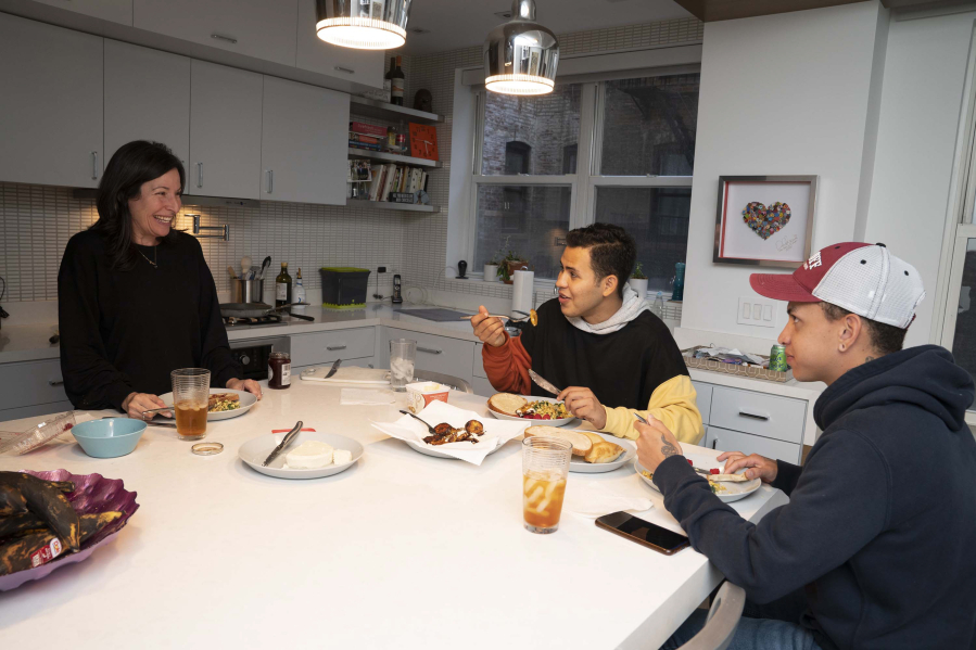 Candice Braun shares a meal with Venezuelan refugees Brandon, right, and Pedro in her apartment on Oct. 7, 2022, in New York. Braun and her husband helped the pair with housing in New York.