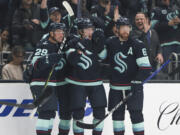 Seattle Kraken center Morgan Geekie, center, celebrates with teammates Vince Dunn (29) and Adam Larsson (6) after scoring a goal during the first period of an NHL hockey game against the Buffalo Sabres, Tuesday, Oct. 25, 2022, in Seattle.