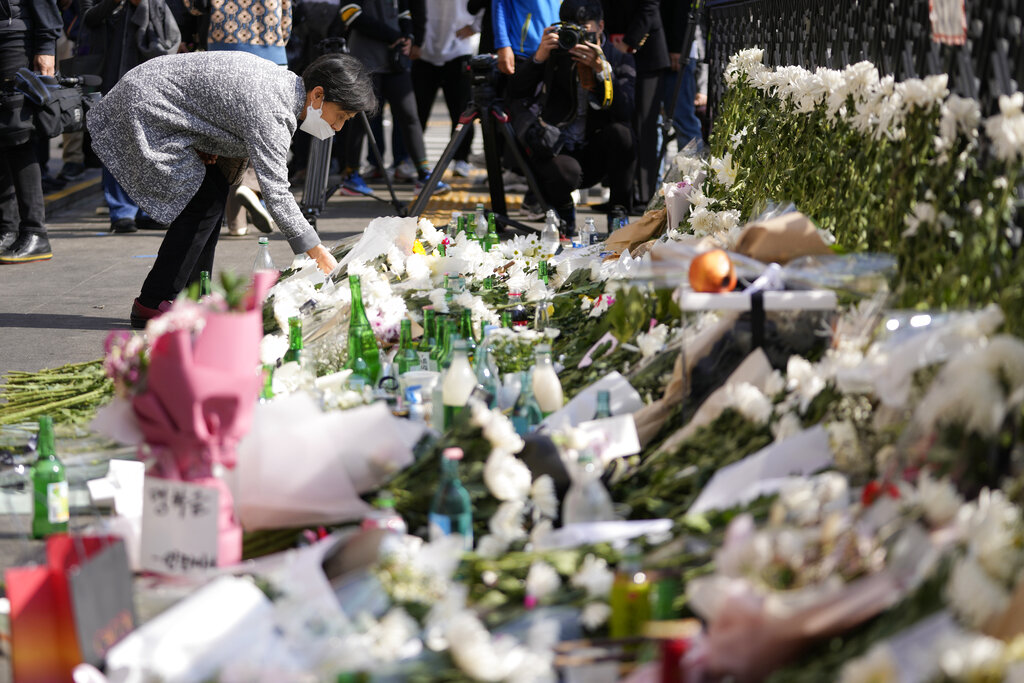 A mourner places flower to pay tribute to victims of a deadly accident following Saturday night's Halloween festivities on the street near the scene in Seoul, South Korea, Monday, Oct. 31, 2022. Police are investigating what caused a crowd surge that killed more than 150 people during Halloween festivities in Seoul over the weekend in the country’s worst disasters in years.
