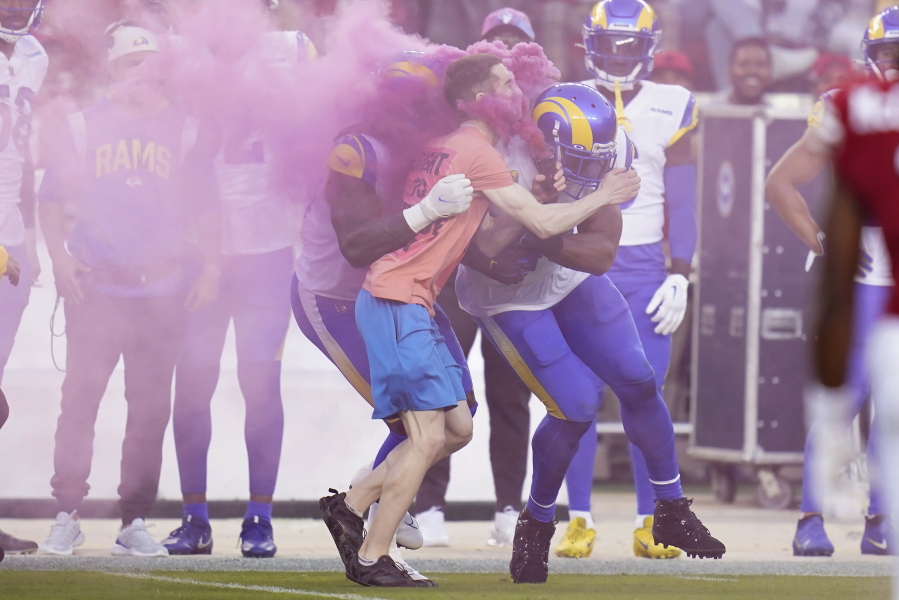 A protester is hit by Los Angeles Rams defensive end Takkarist McKinley, middle left, and linebacker Bobby Wagner during the first half of an NFL football game between the San Francisco 49ers and the Rams in Santa Clara, Calif., Monday, Oct. 3, 2022. (AP Photo/Godofredo A.