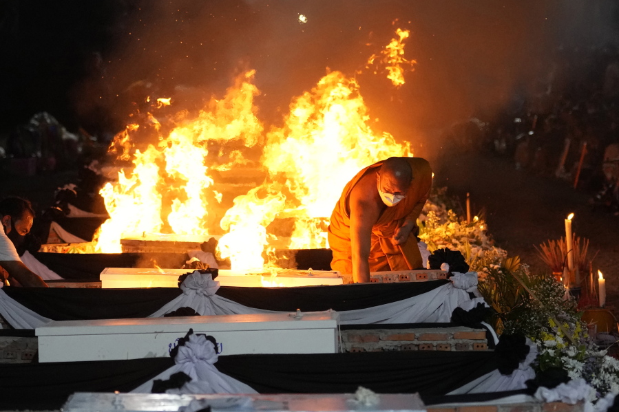 A monk lights funeral pyres to cremate those who died in the day care center attack at Wat Rat Samakee temple in Uthai Sawan, northeastern Thailand, Tuesday, Oct. 11, 2022. A former police officer burst into a day care center in northeastern Thailand on Thursday, killing dozens of preschoolers and teachers before shooting more people as he fled.