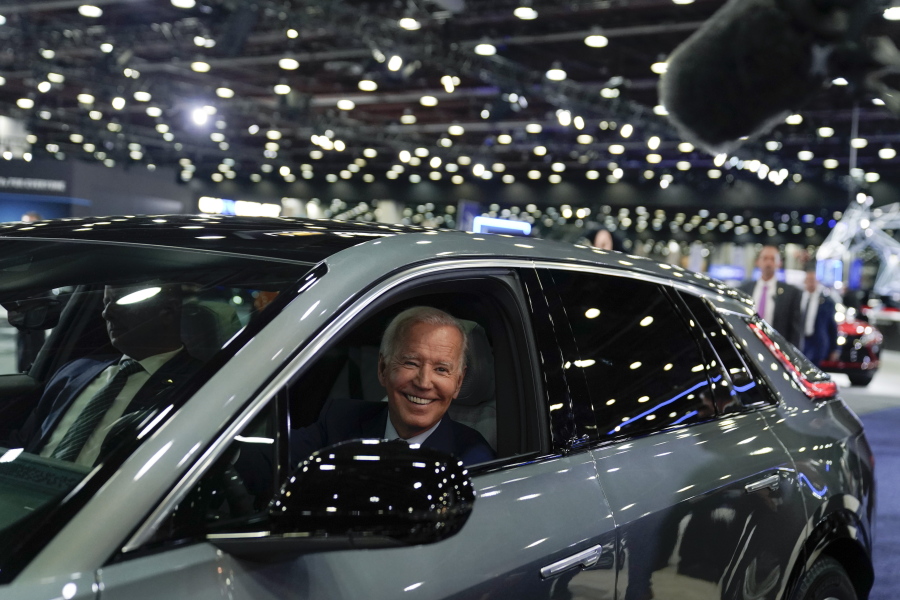 FILE - President Joe Biden drives a Cadillac Lyriq through the showroom during a tour at the Detroit Auto Show, Sept. 14, 2022, in Detroit. Americans are generally more likely to support than oppose many of the government actions on climate change included in the law, a new poll by The Associated Press-NORC Center for Public Affairs Research shows. That includes incentives for electric vehicles and solar panels, though relatively few say they are inclined to pursue either in the next three years.