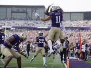 Washington wide receiver Jalen McMillan (11) leaps in the air as he celebrates his touchdown with other team members against Arizona during the first half of an NCAA football game, Saturday, Oct. 15, 2022, in Seattle.