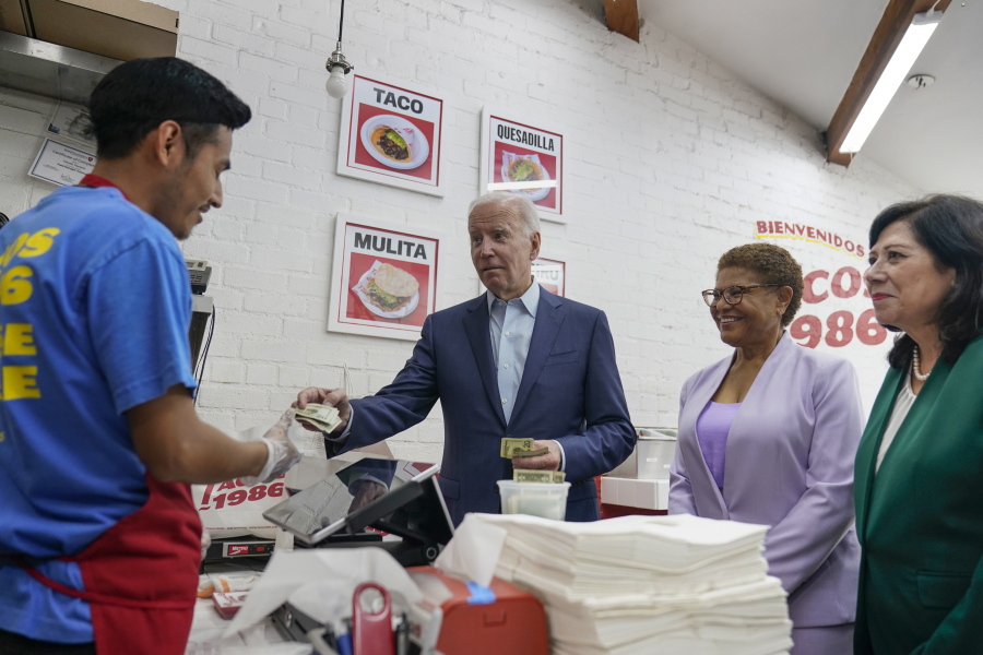 President Joe Biden pays for a takeout order at Tacos 1986, a Mexican restaurant, in Los Angeles, Thursday, Oct. 13, 2022. With the president are Rep. Karen Bass, D, Calif., and Los Angeles County supervisor Hilda Solis.