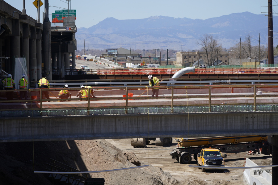 FILE - Workers toil on a bridge over the surface of what will become Interstate 70 north of downtown Denver, as part of a 10-mile-long project, on April 29, 2021. The White House will host a summit Thursday, Oct. 13, 2022, to help speed up construction projects tied to the roughly $1 trillion infrastructure law -- an effort to improve coordination with the mayors and governors who directly account for 90% of the spending.