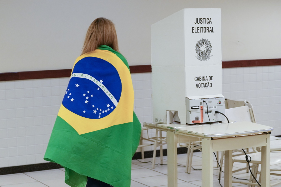 A voter wrapped in a Brazilian flag arrives to vote in a presidential a run-off pitting President Jair Bolsonaro against former President Luiz In?cio Lula da Silva, in Brasilia, Brazil, Sunday, Oct. 30, 2022.