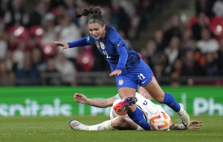 United States' Sophia Smith challenges for the ball with England's Millie Bright, bottom, during the women's friendly soccer match between England and the US at Wembley stadium in London, Friday, Oct. 7, 2022.