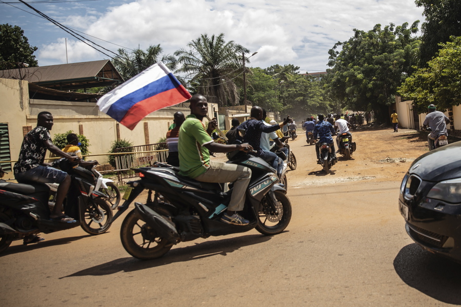 Supporters of Capt. Ibrahim Traore parade waving a Russian flag in the streets of Ouagadougou, Burkina Faso, Sunday, Oct. 2, 2022. Burkina Faso's new junta leadership is calling for calm after the French Embassy and other buildings were attacked. The unrest following the West African nation's second coup this year came after a junta statement alleged that the ousted interim president was at a French military base in Ouagadougou. France vehemently denied the claim and has urged its citizens to stay indoors amid rising anti-French sentiment in the streets.