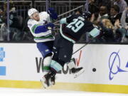Vancouver Canucks left wing Nils Hoglander (21) collides with Seattle Kraken defenseman Vince Dunn (29) as they battle for the puck during the first period of an NHL hockey game, Thursday, Oct. 27, 2022, in Seattle.