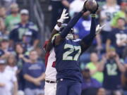 Seattle Seahawks cornerback Tariq Woolen (27) intercepts a pass intended for Arizona Cardinals wide receiver Marquise Brown, rear, during the second half of an NFL football game in Seattle, Sunday, Oct. 16, 2022.