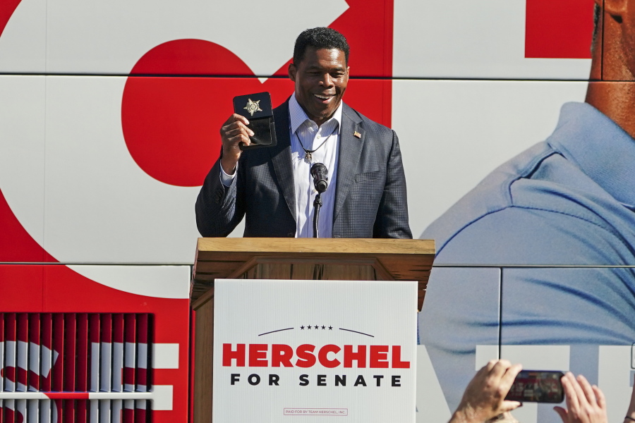 Herschel Walker, Republican candidate for U.S. Senate in Georgia, flashes a police badge as he speak to supporters during a campaign rally Tuesday, Oct. 18, 2022, in Atlanta.
