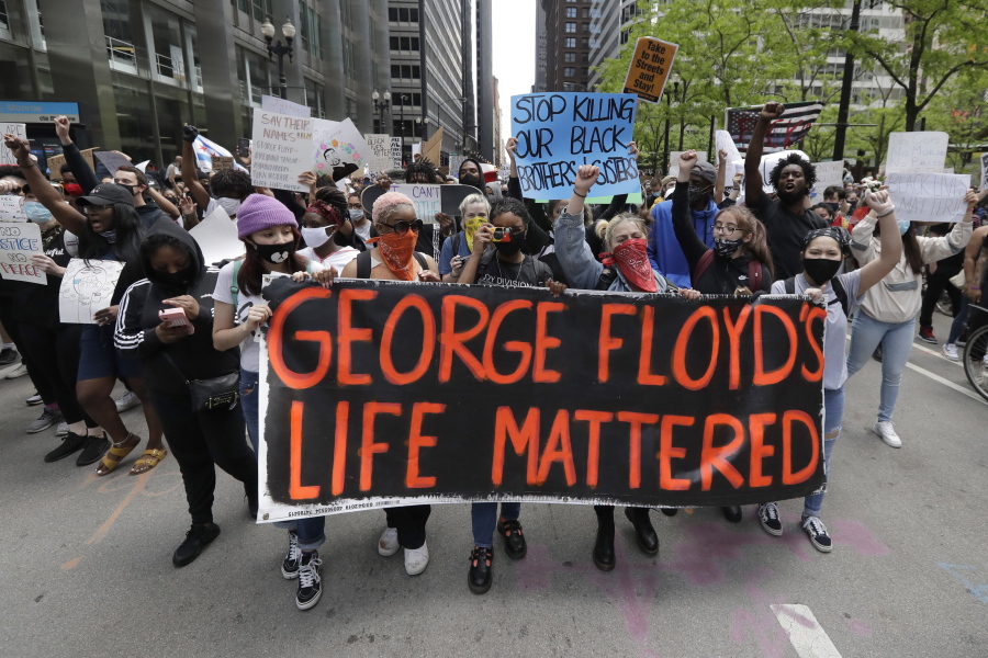 FILE - Protesters hold signs as they march during a protest over the death of George Floyd in Chicago on May 30, 2020. Two former Minneapolis police officers charged in Floyd's death are heading to trial on state aiding and abetting counts, the third and likely final criminal proceeding in a killing that mobilized protesters worldwide against racial injustice in policing. (AP Photo/Nam Y.