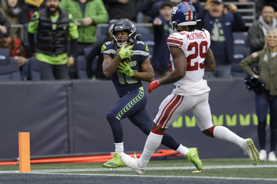 Seattle Seahawks wide receiver Tyler Lockett, left, scores a touchdown past New York Giants safety Xavier McKinney (29) during the second half of an NFL football game in Seattle, Sunday, Oct. 30, 2022.