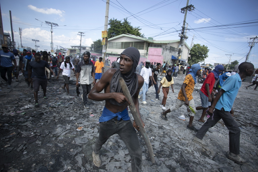 A protester carries a piece of wood simulating a weapon during a protest demanding the resignation of Prime Minister Ariel Henry, in the Petion-Ville area of Port-au-Prince, Haiti, Monday, Oct. 3, 2022.