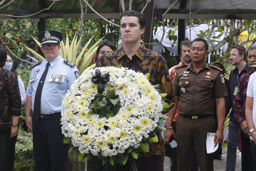 Australian Assistant Minister for Foreign Affairs Tim Watts, center, carries a wreath during the commemoration of the 20th anniversary of the Bali bombing that killed 202 people, mostly foreign tourists, including 88 Australians and seven Americans, at the Australian Consulate in Denpasar, Bali, Indonesia on Wednesday, Oct. 12, 2022. Services were held simultaneously in several places in Australia and at Bali's Australian Consulate in the city of Denpasar, where Australian survivors and relatives of the deceased were among the 200 in attendance to pay tribute to their loved ones who died in the most popular tourist area on the island two decades ago.