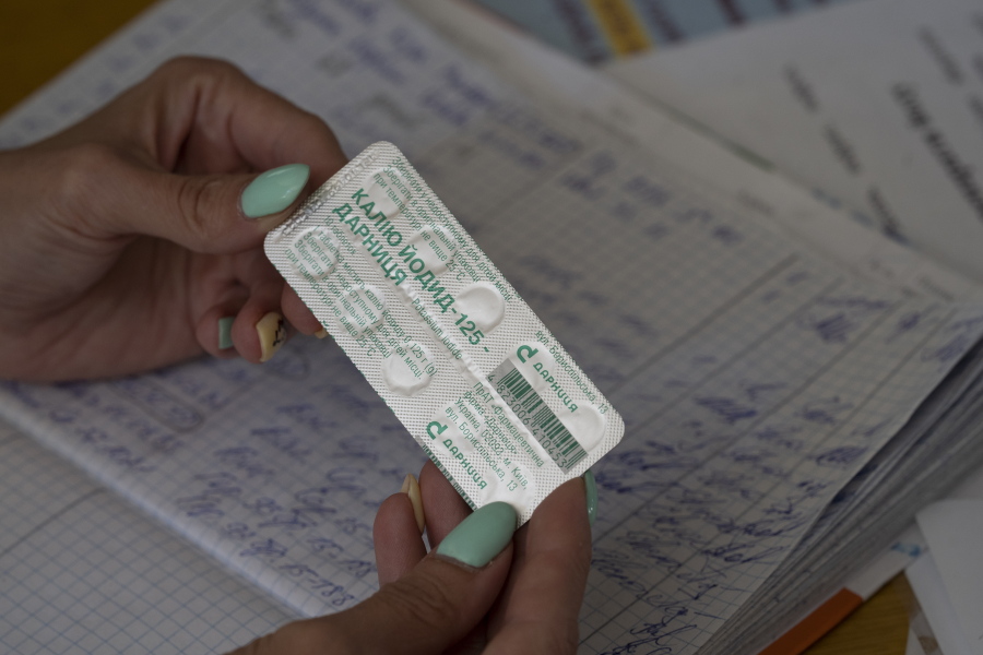 FILE - A woman shows a pack with iodine tablets before distributing them to residents at a local school in case of a radiation leak in Zaporizhzhia, Ukraine, Friday, Sept. 2, 2022. The war in Ukraine has heightened fears about nuclear exposure -- and interest in iodine pills that can help protect the body from some radiation.