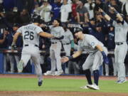 Seattle Mariners' Adam Frazier, left, and Cal Raleigh celebrate after scoring on a three-RBI double off the bat of J.P. Crawford (not shown) against the Toronto Blue Jays during the eighth inning of Game 2 of a baseball AL wild-card playoff series Saturday, Oct. 8, 2022, in Toronto.