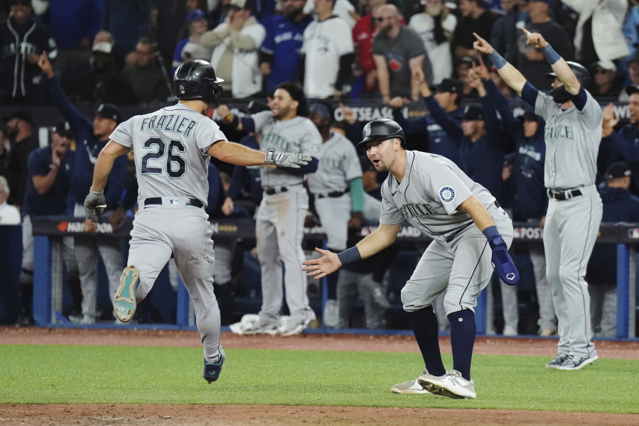 Seattle Mariners' Adam Frazier, left, and Cal Raleigh celebrate after scoring on a three-RBI double off the bat of J.P. Crawford (not shown) against the Toronto Blue Jays during the eighth inning of Game 2 of a baseball AL wild-card playoff series Saturday, Oct. 8, 2022, in Toronto.