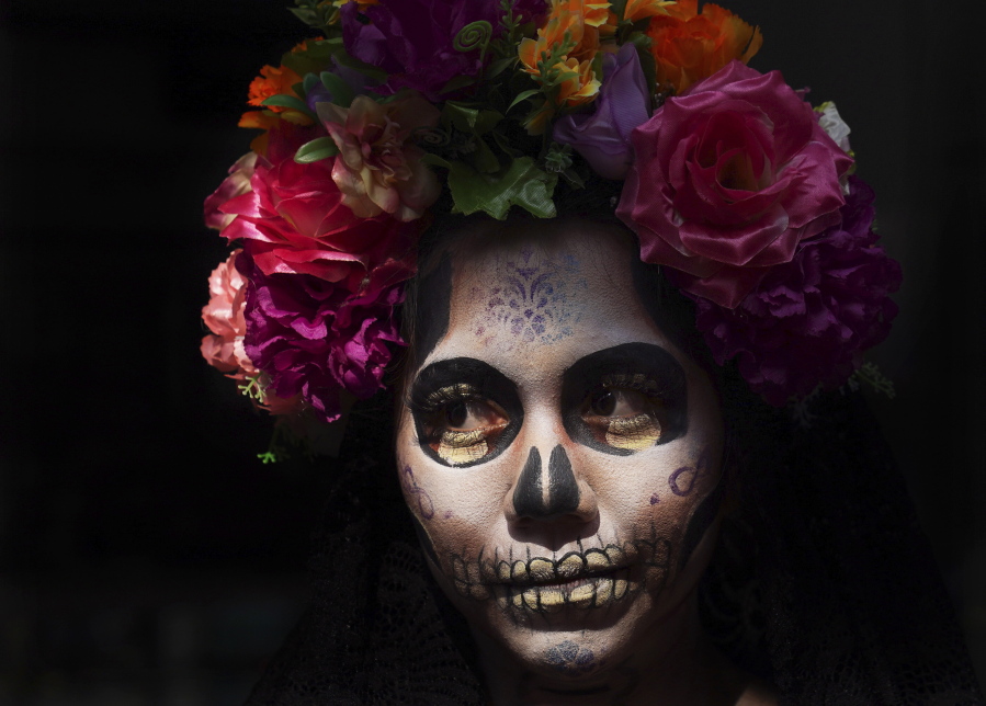 A woman dressed as "Catrina" poses for tourists in Mexico City's square, the Zocalo, as part of the Day of the Dead festivities in Mexico City, on Friday.