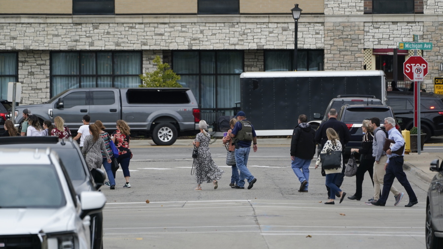 Police evacuate people from buildings near the Hampton Inn in Dearborn, Mich., Thursday, Oct. 6, 2022. Police negotiated Thursday afternoon with a suspected gunman inside the suburban Detroit hotel after reports of gunfire led to evacuations and lockdowns in a popular dining and shopping area.