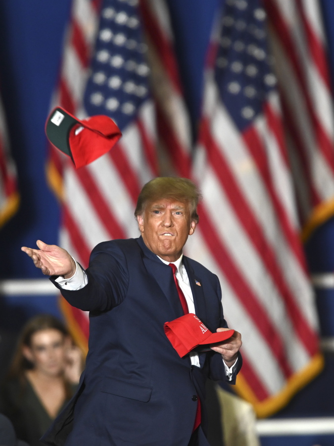 Former President Donald Trump tosses caps to the crowd as he steps onstage during a rally at the Macomb Community College Sports & Expo Center in Warren, Mich., Saturday, Oct. 1, 2022.