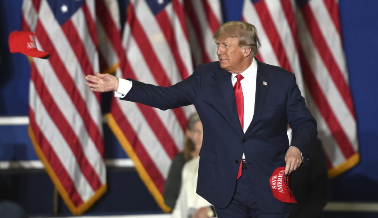 Former President Donald Trump tosses caps to the crowd as he steps onstage during a rally at the Macomb Community College Sports & Expo Center in Warren, Mich., Saturday, Oct. 1, 2022.