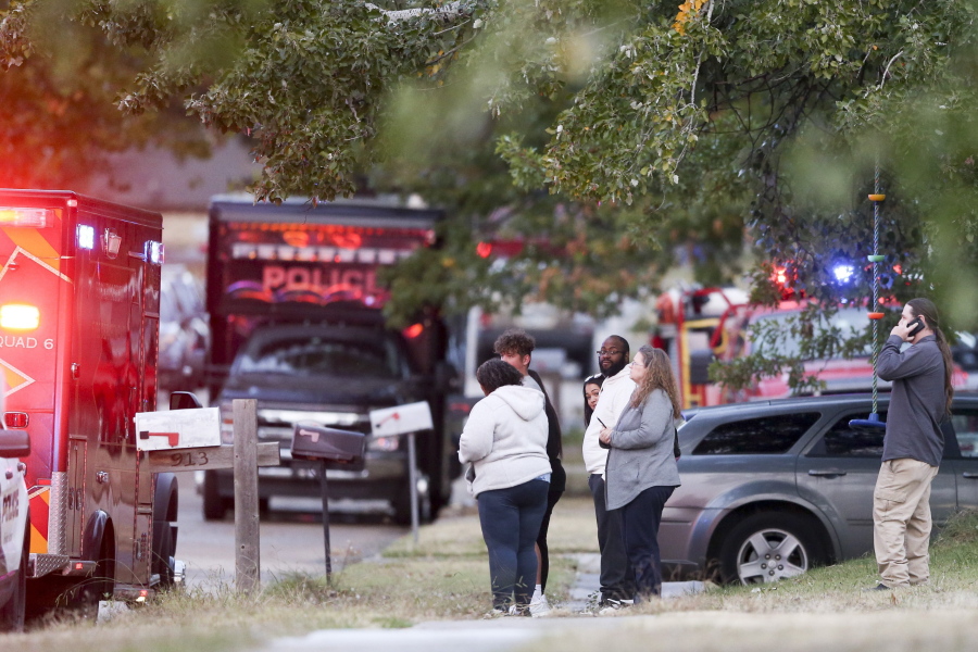 People look on as Broken Arrow, Okla., police and fire department investigate the scene of a fire with multiple fatalities at the corner South Hickory Ave. and West Galveston St. on Thursday, Oct. 27, 2022. Eight people were found dead Thursday after a fire was extinguished at a Tulsa-area house, and police said they were investigating the deaths as homicides.