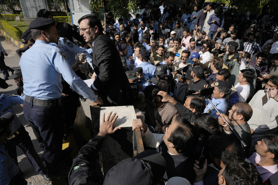 Police officers block the main gate to stop supporters of former Prime Minister Imran Khan's party from entering the Election Commission head office in Islamabad, Pakistan, Friday, Oct. 21, 2022. The elections commission on Friday disqualified Khan from holding public office on charges of unlawfully selling state gifts to him and concealing assets, his spokesman said.