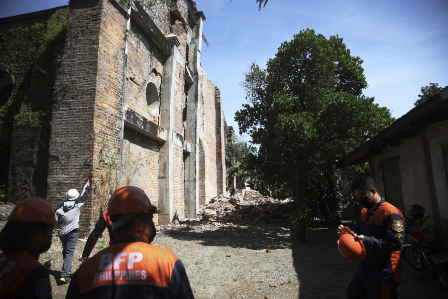 Firemen stand beside a damaged church after a strong earthquake at Ilocos Norte, Northern Philippines on Wednesday Oct. 26, 2022. A strong earthquake rocked a large swathe of the northern Philippines, injuring multiple people and forcing the closure of an international airport and the evacuation of patients in a hospital, officials said Wednesday.