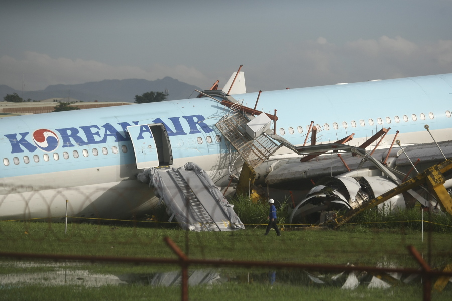 A man walks beside a damaged Korean Air plane after it overshot the runway at the Mactan-Cebu International Airport in Cebu, central Philippines early Monday Oct. 24, 2022. The Korean Air plane overshot the runway while landing in bad weather in the central Philippines late Sunday, but authorities said all 173 people on board were safe.