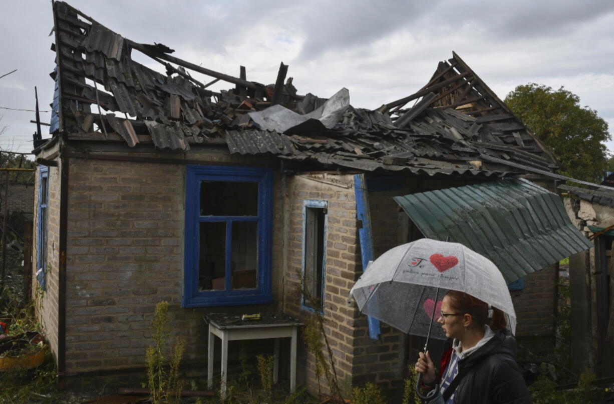 Local resident Ekaterina, 22, stands next to her residential building that was damaged after an overnight Russian attack in Kramatorsk, Ukraine, Tuesday, Oct. 4, 2022.