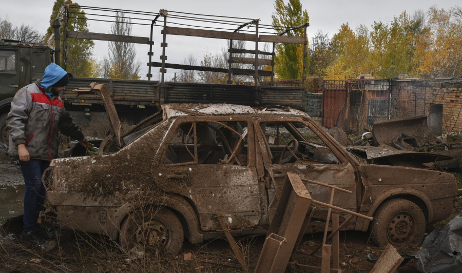 A local resident stands next to his car that was damaged after an overnight Russian attack in Kramatorsk, Ukraine, Thursday, Oct. 27, 2022.