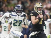 New Orleans Saints' Taysom Hill heads to the end zone for a 60 yard rushing touchdown as Seattle Seahawks' Tariq Woolen pursues during an NFL football game in New Orleans, Sunday, Oct. 9, 2022.