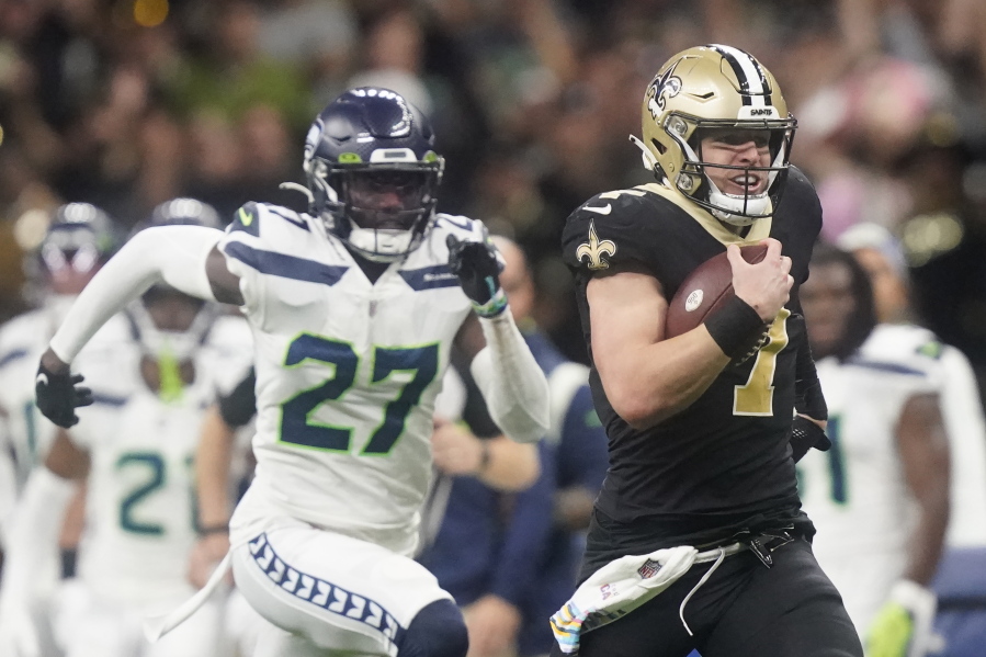 New Orleans Saints' Taysom Hill heads to the end zone for a 60 yard rushing touchdown as Seattle Seahawks' Tariq Woolen pursues during an NFL football game in New Orleans, Sunday, Oct. 9, 2022.