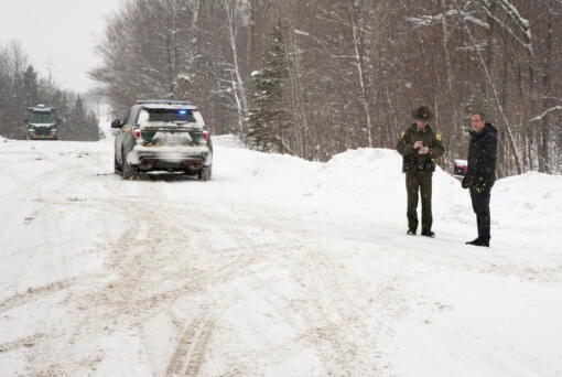 FILE -- A Vermont State Trooper, center, speaks to a homeowner, Thursday, Jan. 8, 2018, near an area on Peacham Road, in Barnet, Vt., where the body of Gregory Davis was found. Los Angeles biotech investor Serhat Gumrukcu pleaded not guilty Tuesday, Oct. 4, 2022, in a transcontinental murder-for-hire conspiracy that led to the 2018 abduction and killing of Gregory Davis.