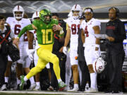 Oregon quarterback Bo Nix (10) runs past Stanford coach David Shaw, right, on a long gain during the first half of an NCAA college football game Saturday, Oct. 1, 2022, in Eugene, Ore.