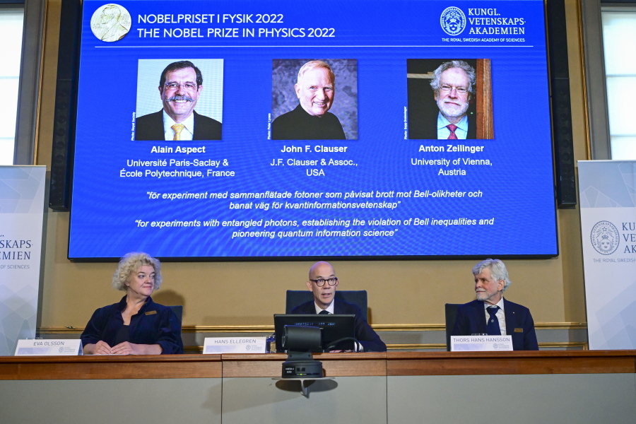 Secretary General of the Royal Swedish Academy of Sciences Hans Ellegren, centre, Eva Olsson, left and Thors Hans Hansson, members of the Nobel Committee for Physics announce the winner of the 2022 Nobel Prize in Physics, from left to right on the screen, Alain Aspect, John F. Clauser and Anton Zeilinger, during a press conference at the Royal Swedish Academy of Sciences, in Stockholm, Sweden, Tuesday, Oct. 4, 2022.