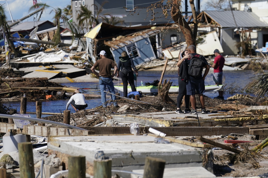 People stand on the destroyed bridge to Pine Island as they view the damage in the aftermath of Hurricane Ian in Matlacha, Fla., Sunday, Oct. 2, 2022. The only bridge to the island is heavily damaged so it can only be reached by boat or air.