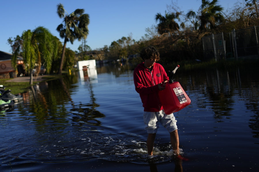 Jose Cruz, 13, carries an empty Jerrycan through receding flood waters outside his house as his family heads out to look for supplies, three days after the passage of Hurricane Ian, in Fort Myers, Fla., Saturday, Oct. 1, 2022.