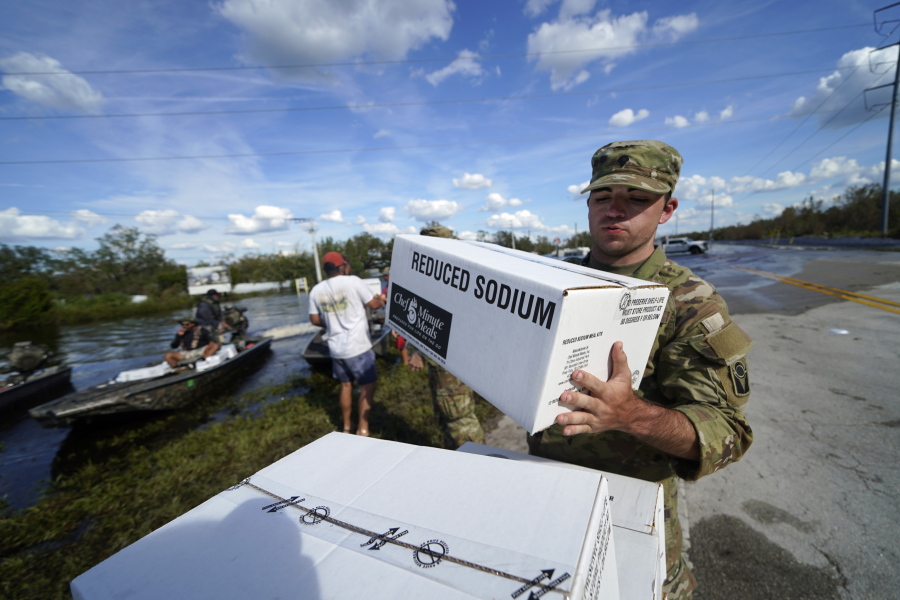 A member of the Florida National Guard helps stack emergency supplies that arrived by boat during flooding along the Peace River in the aftermath of Hurricane Ian in Arcadia, Fla., Monday, Oct. 3, 2022.