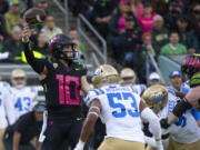 Oregon's Bo Nix, left, throws down field ahead UCLA's Darius Muawai during the first half in an NCAA college football game Saturday, Oct. 22, 2022, in Eugene, Ore.