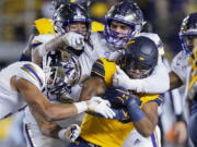 California running back DeCarlos Brooks (25) is tackled by Washington safety Alex Cook and defensive linemen Tuli Letuligasenoa and Bralen Trice Washington, from left, during the first half of an NCAA college football game in Berkeley, Calif., Saturday, Oct. 22, 2022. (AP Photo/Godofredo A.